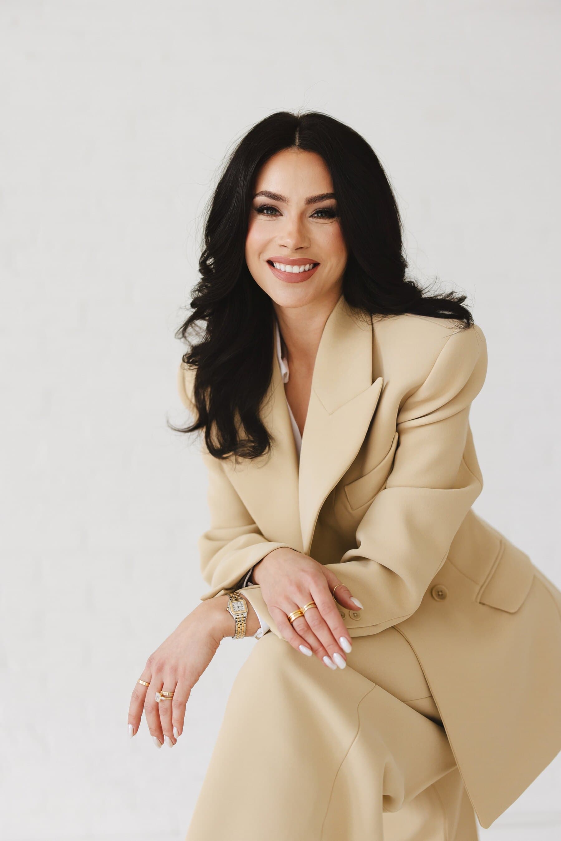 Nicole Talacha seated in a cream suit